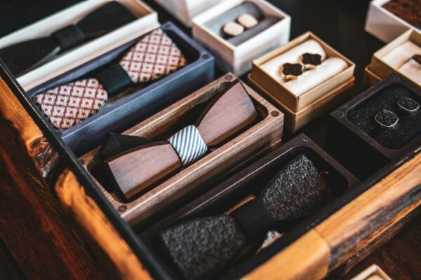 A collection of wooden bow ties displayed elegantly in a drawer, showcasing luxury menswear accessories.