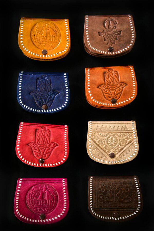 A vibrant collection of handmade leather bags displayed against a black background.