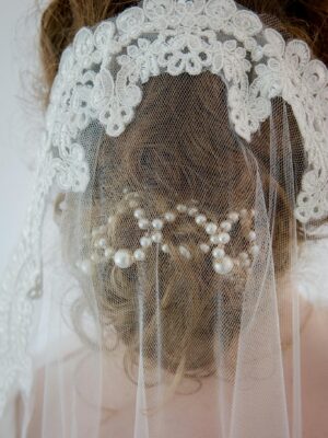 Close-up of a bride's intricate lace veil adorned with pearls, showcasing elegance and sophistication.