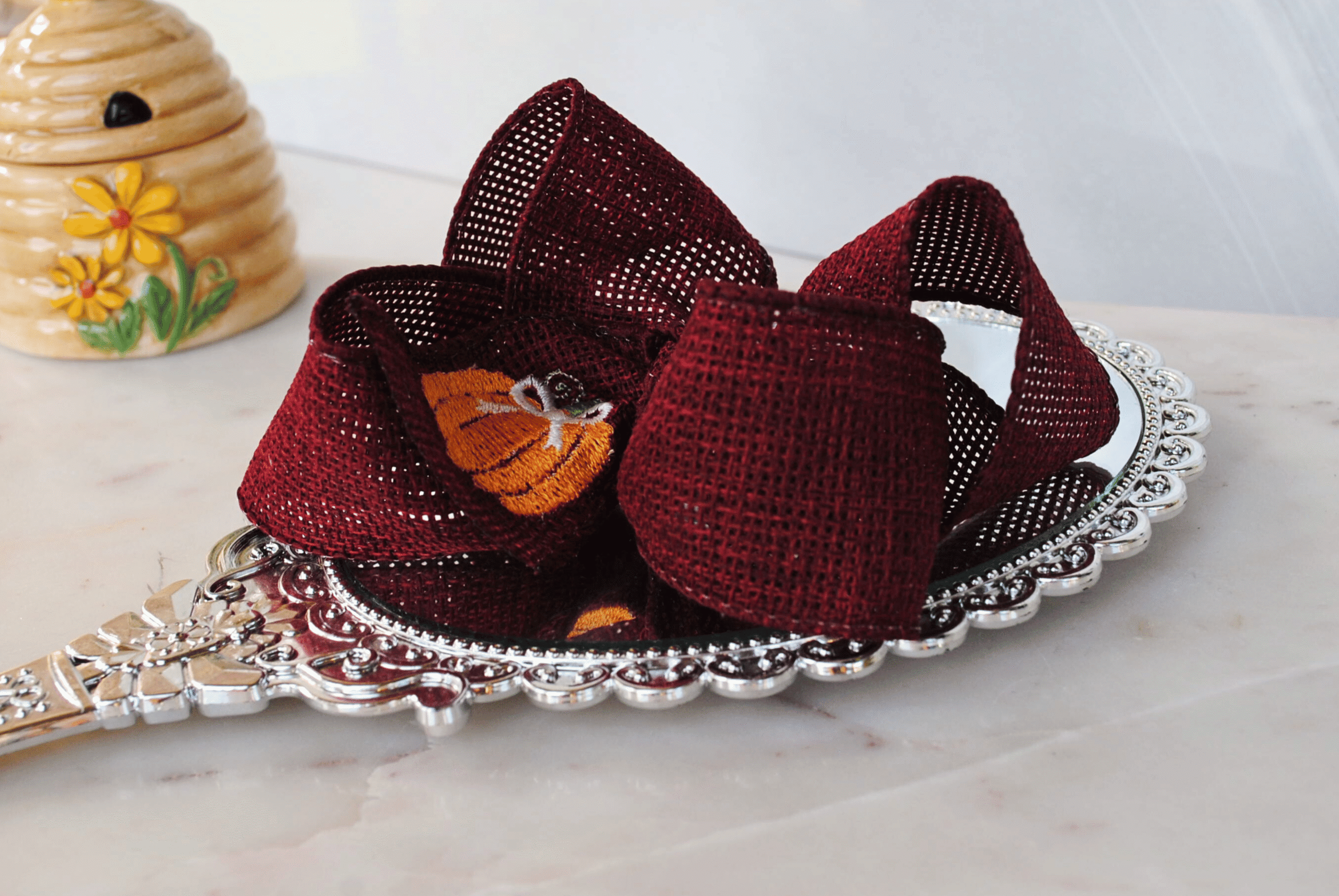 Side view of pumpkin bow that has been stitched on cranberry burlap.