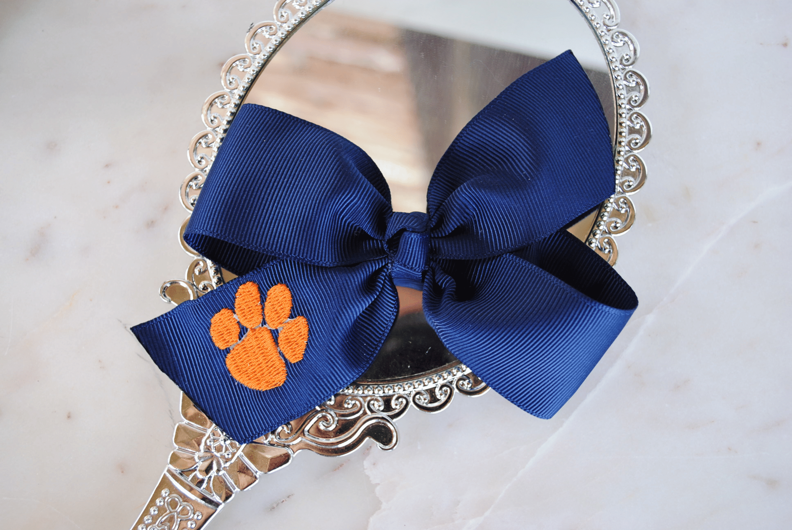 Flat navy pinwheel bow with embroidered paw print