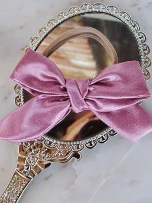 a luxe baby headband in rose pink satin on a marble top