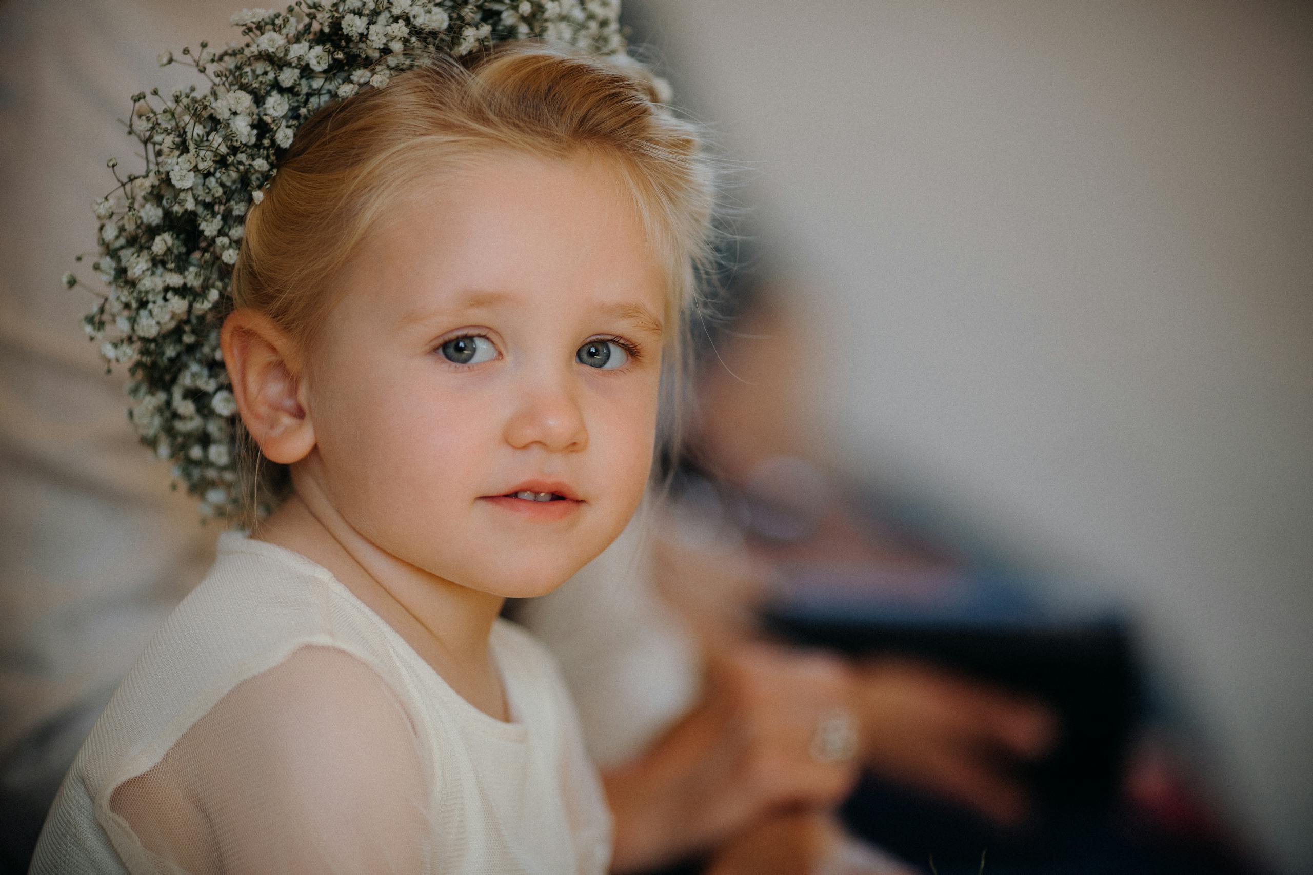 Adorable child with floral crown looking serene, indoors.