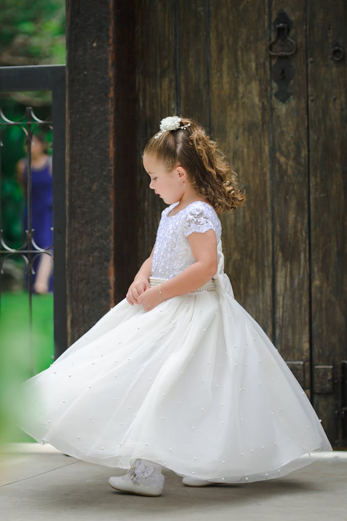 Charming flower girl wearing a beautiful white dress at a wedding event.