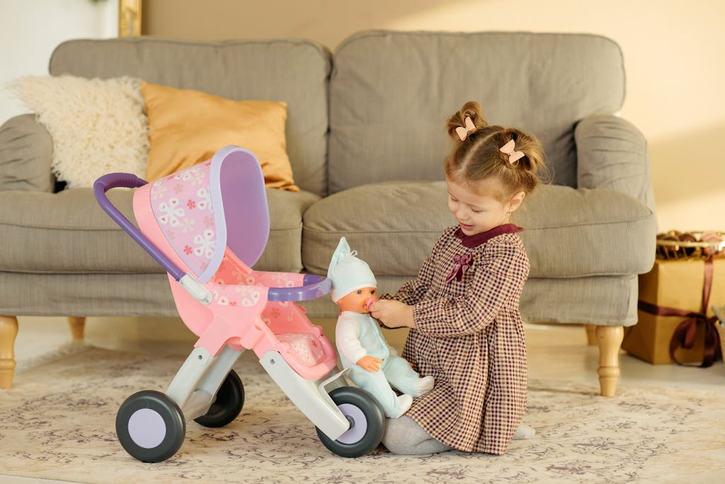 Speaking Life While You Braid: What to Say During Morning Hair Time 4 Adorable child playing with a doll and stroller in a cozy living room setting.