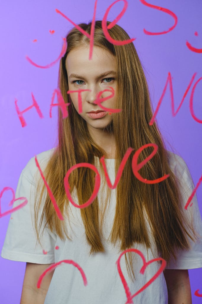 Five Ways to Protect the Season of Girlhood in a Culture That Wants to Steal It 5 Teen girl posing behind glass with emotional text art on vibrant pink background in a studio.