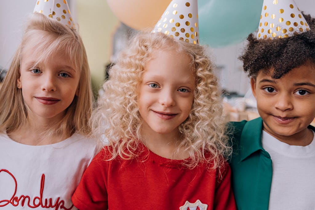Protective Styles for Curly Kids: Low-Tension Looks That Stay Put 4 girl with curly hair at a birthday party with party hats, smiling and enjoying the celebration.